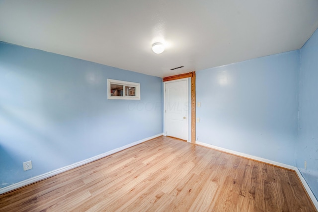 empty room with visible vents, baseboards, and wood finished floors