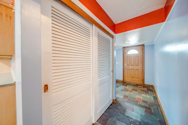 doorway with baseboards and stone tile flooring