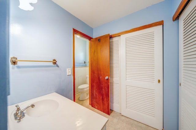 bathroom featuring toilet, a closet, and a sink