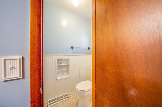 bathroom featuring tile patterned floors, toilet, visible vents, and wainscoting