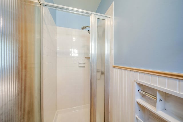 bathroom featuring a shower stall and a wainscoted wall