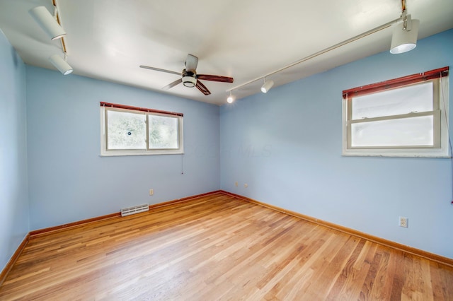 unfurnished room with visible vents, wood finished floors, and rail lighting