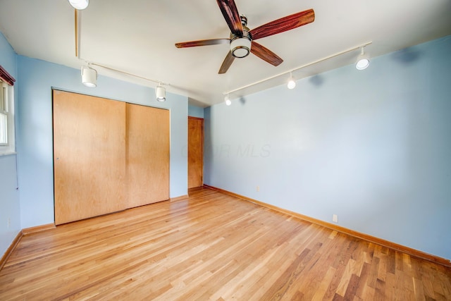 unfurnished bedroom featuring track lighting, two closets, and light wood-style floors