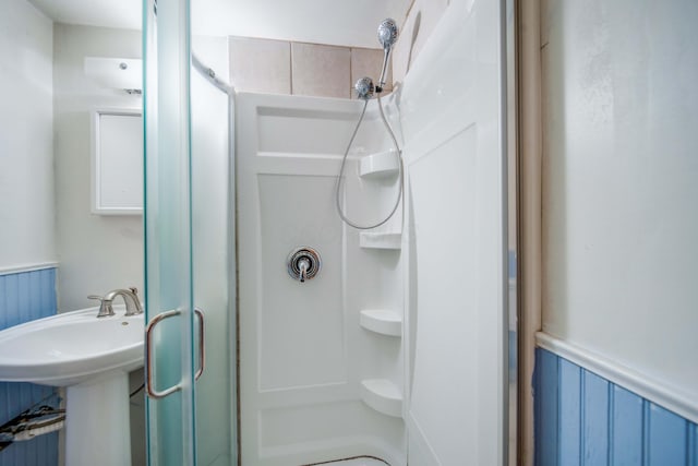 full bathroom featuring a sink, a stall shower, and wainscoting