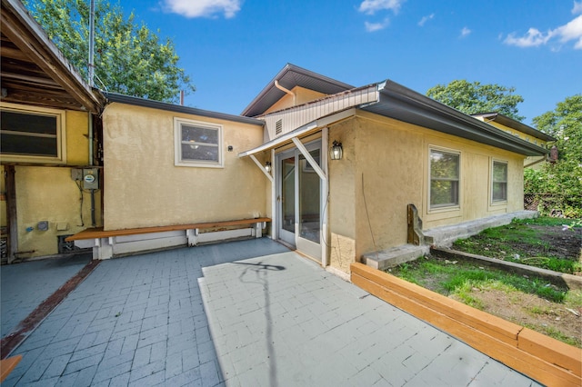 back of property with a patio and stucco siding