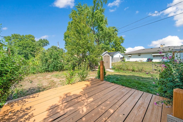 wooden deck with a storage unit, a lawn, an outdoor structure, and fence