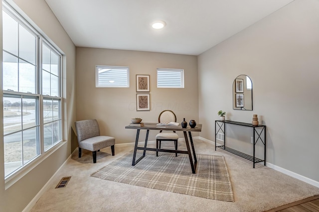 office space with light carpet, visible vents, and baseboards