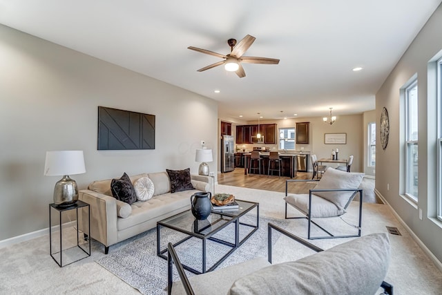 living area featuring ceiling fan with notable chandelier, recessed lighting, baseboards, and visible vents