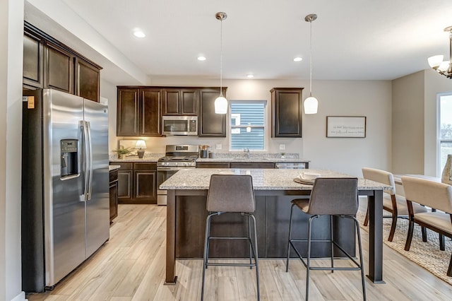 kitchen with dark brown cabinets, a kitchen bar, appliances with stainless steel finishes, and a healthy amount of sunlight