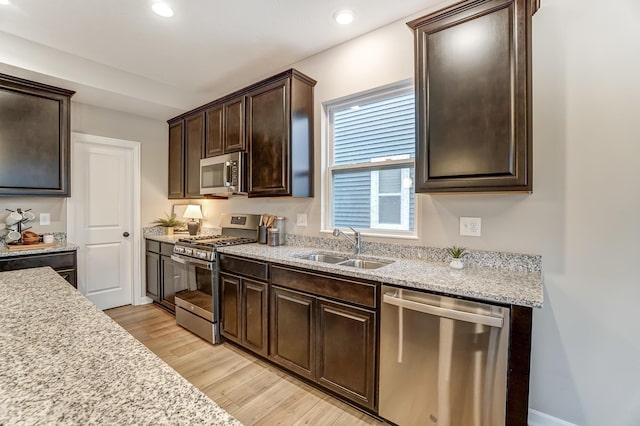 kitchen with light wood-style flooring, recessed lighting, a sink, dark brown cabinetry, and appliances with stainless steel finishes