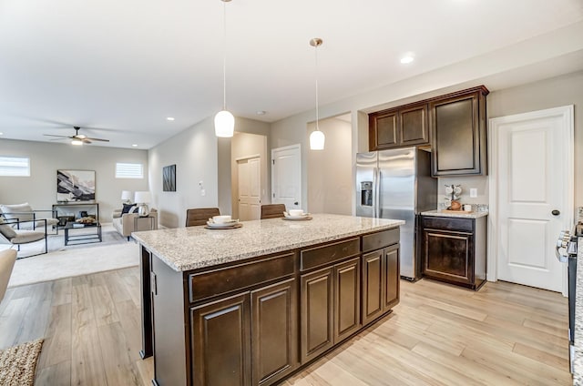 kitchen featuring a kitchen island, dark brown cabinetry, decorative light fixtures, light wood-style floors, and stainless steel refrigerator with ice dispenser