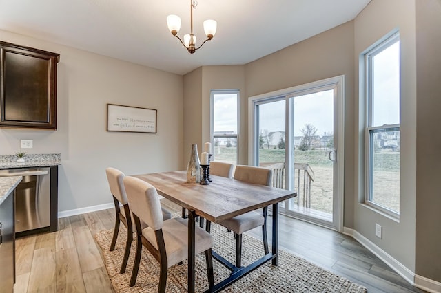 dining room with a notable chandelier, baseboards, and light wood-style floors