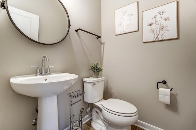 bathroom featuring toilet, baseboards, and a sink