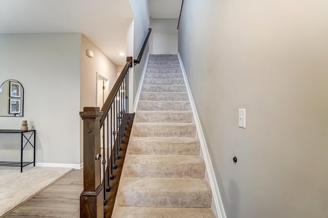 staircase featuring wood finished floors and baseboards