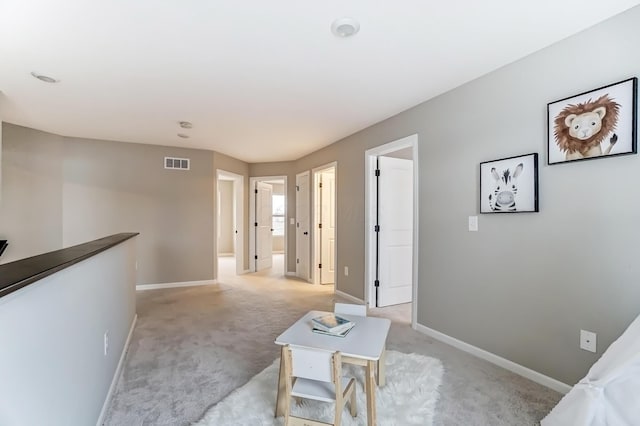 interior space with visible vents, baseboards, light colored carpet, and an upstairs landing