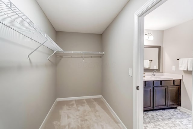 walk in closet with a sink and light colored carpet