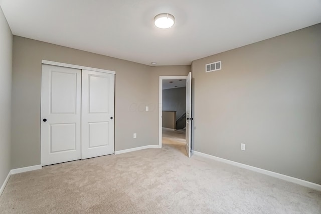 unfurnished bedroom featuring a closet, visible vents, light colored carpet, and baseboards