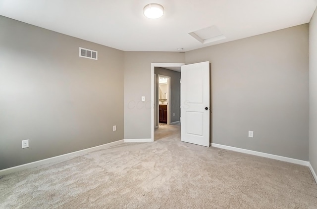 unfurnished room with attic access, baseboards, and visible vents