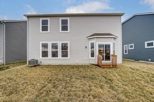 rear view of house featuring central AC unit and a yard