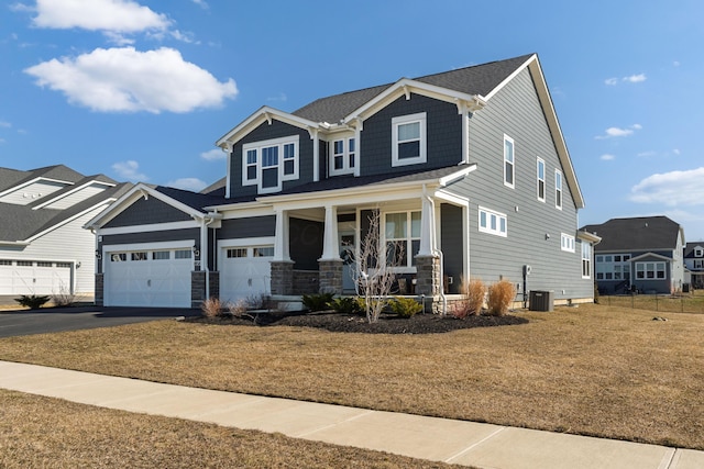 craftsman-style home with aphalt driveway, central air condition unit, and covered porch