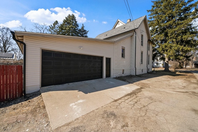 exterior space with an attached garage, driveway, and fence