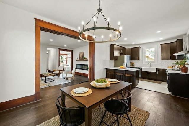 dining space with a glass covered fireplace, hardwood / wood-style flooring, recessed lighting, and baseboards