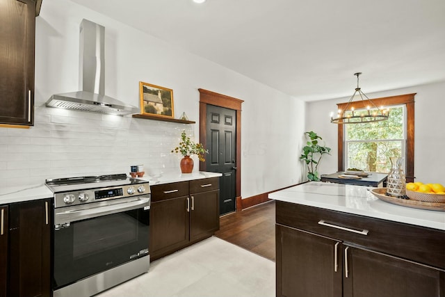 kitchen featuring dark brown cabinetry, backsplash, stainless steel range with electric stovetop, and wall chimney range hood