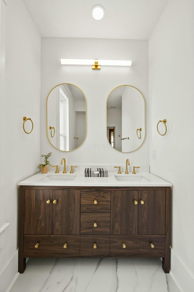 bathroom with a sink, marble finish floor, and double vanity