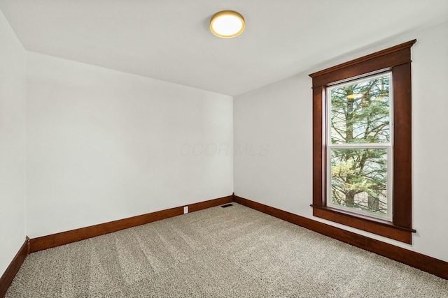 carpeted spare room featuring visible vents and baseboards