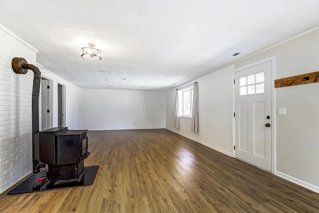 living area featuring a wood stove, wood finished floors, baseboards, and a textured ceiling