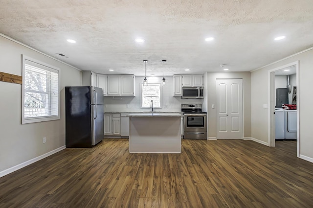 kitchen featuring washer and dryer, dark wood-type flooring, a sink, and stainless steel appliances