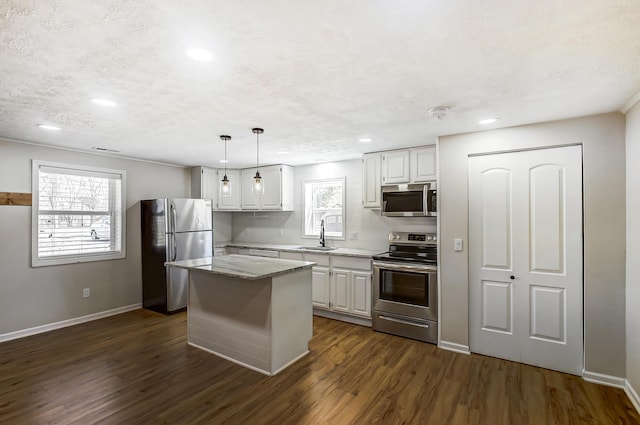 kitchen with dark wood-style flooring, a sink, stainless steel appliances, white cabinets, and a center island