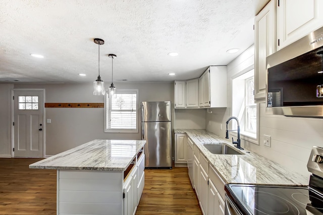 kitchen with appliances with stainless steel finishes, a center island, dark wood-type flooring, and a sink