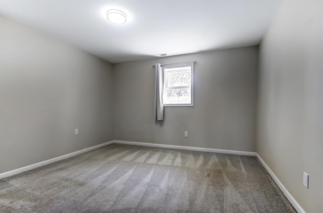 carpeted spare room with visible vents and baseboards