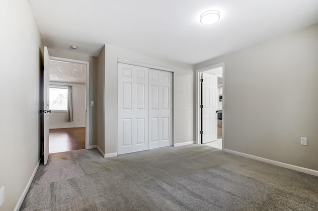 unfurnished bedroom with a closet, baseboards, and carpet