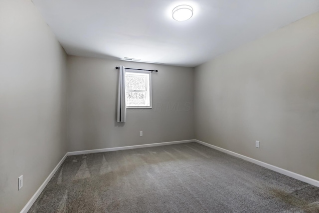 carpeted spare room featuring baseboards and visible vents