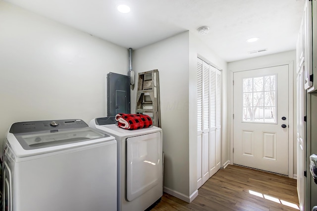 laundry room with wood finished floors, visible vents, laundry area, electric panel, and separate washer and dryer