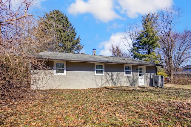 rear view of property with a yard, stucco siding, and central AC