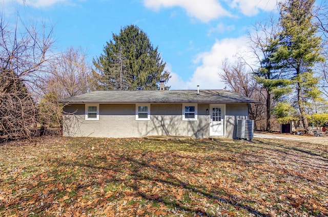 back of house featuring central AC unit and stucco siding