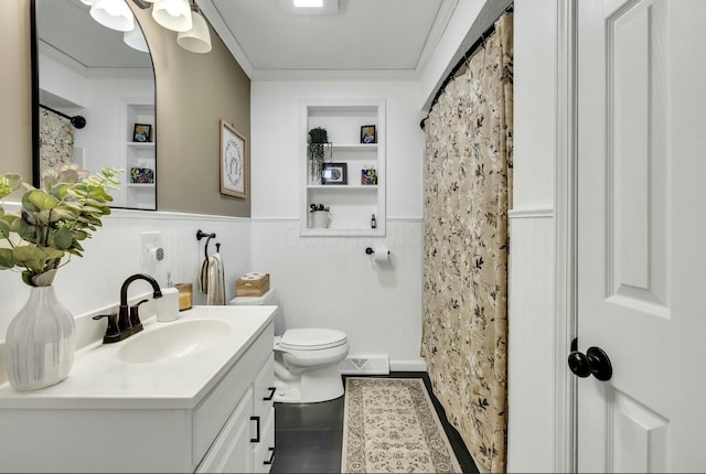 full bath with built in shelves, toilet, wainscoting, crown molding, and vanity