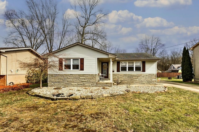 ranch-style home with stone siding, a front yard, and fence