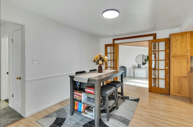 dining room featuring light wood-style floors, baseboards, and french doors