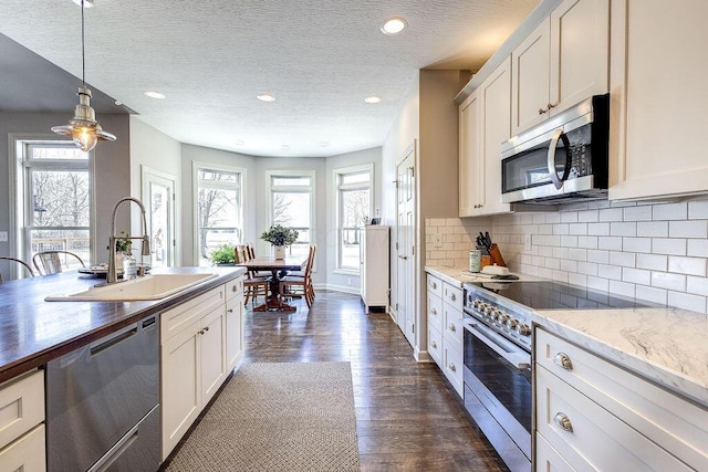 kitchen with a wealth of natural light, decorative backsplash, stainless steel appliances, and a sink