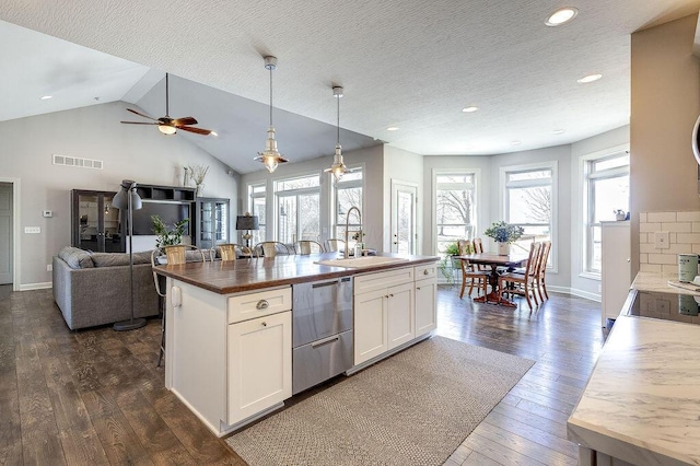 kitchen featuring visible vents, a sink, wood counters, open floor plan, and dark wood-style flooring