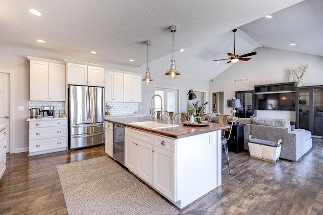 kitchen featuring dark wood-type flooring, a breakfast bar, appliances with stainless steel finishes, white cabinets, and a sink