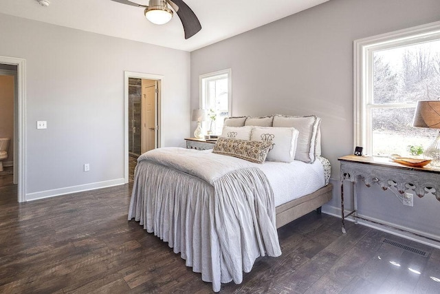 bedroom featuring a ceiling fan, wood finished floors, visible vents, baseboards, and ensuite bathroom