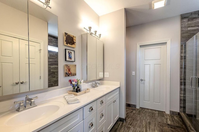 bathroom with double vanity, a tile shower, wood finished floors, and a sink