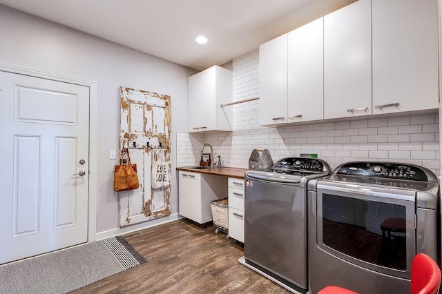 clothes washing area featuring dark wood-type flooring, washer and clothes dryer, recessed lighting, cabinet space, and a sink