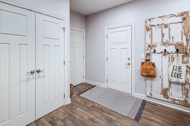 foyer entrance featuring visible vents, baseboards, and wood finished floors