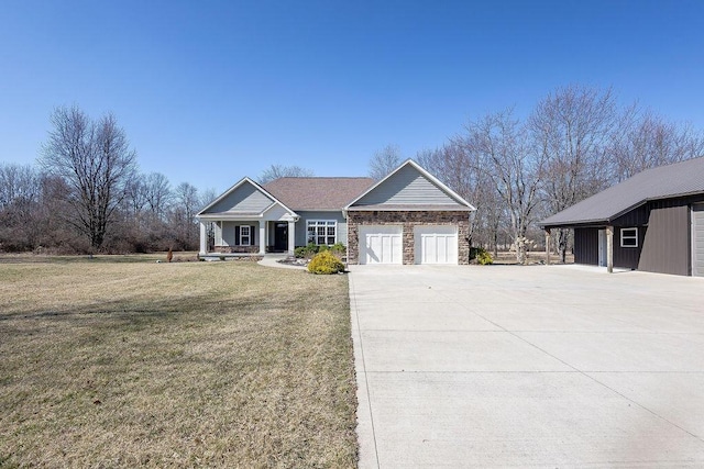 view of front of property featuring stone siding, an attached garage, concrete driveway, and a front yard